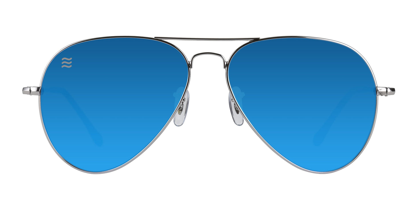 Neven Eyewear's H2O aviator sunglasses feature metallic silver stainless steel frames and bright blue mirrored polarized lenses with a small white wavy logo in the top left. Nose pads and thin arms are visible against a white background.