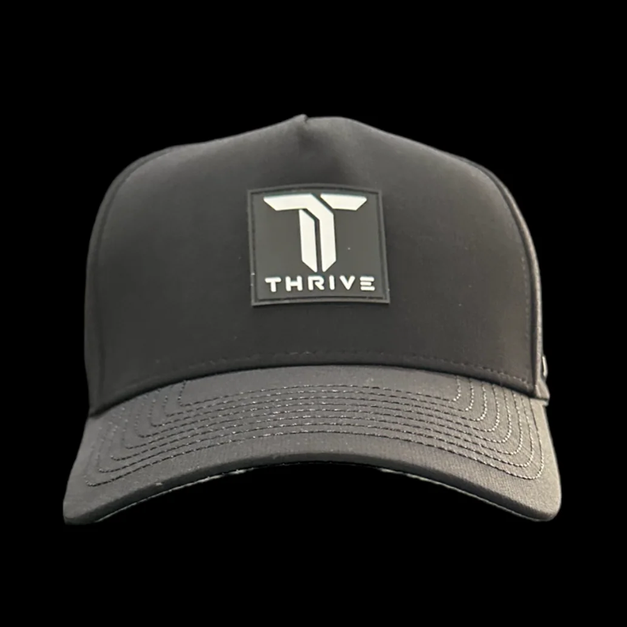 The Thrive Elite Tour Hat by Thrive Pickleball is a black cap with a curved brim, featuring a rectangular patch on the front with a bold white and gray T logo above "THRIVE" in white capitals.