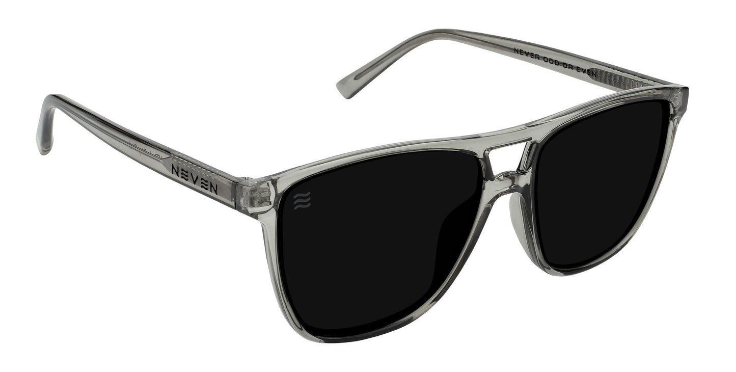 The Rip Tide by Neven Eyewear features a transparent gray plastic frame with large, dark polarized lenses offering UV400 protection. A silver hinge and NEVEN on the left arm add a modern touch, perfect for Indian Harbor Beach.