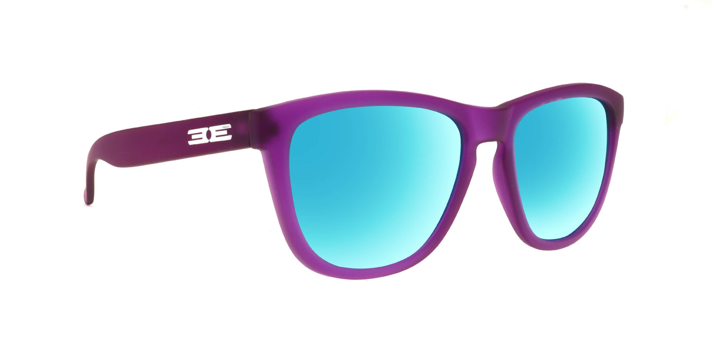 Epoch Eyewear's VIBE sunglasses feature a matte purple frame, blue mirrored lenses, and a white BE logo on the left arm. These luxury sunglasses are shown against a plain white background.
