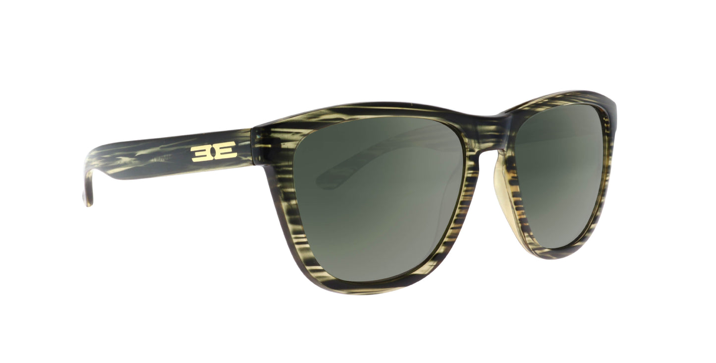 Epoch Eyewear’s VIBE sunglasses feature dark green lenses and a marbled green-yellow frame with a bold gold “BE” logo on the left temple, displayed against a white background.