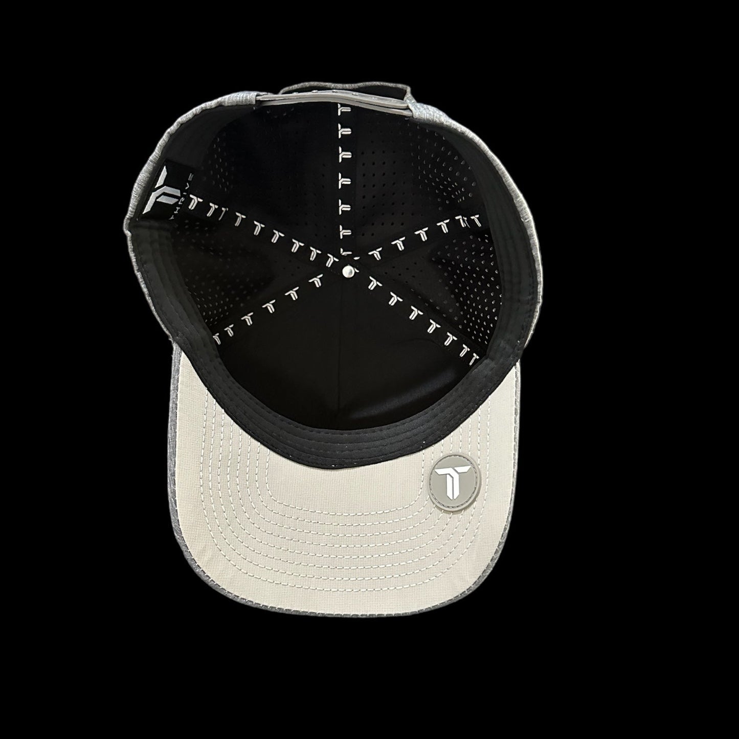 The Thrive Pickleball Thrive Elite Tour Hat is a light gray baseball cap seen from above, revealing black lining with repeated “T” logos, a round “T” logo patch underneath, and perforated black fabric panels for performance.