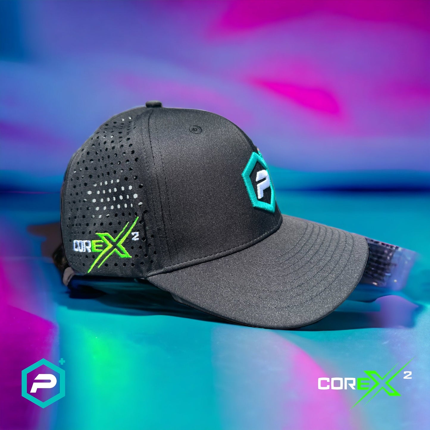 The Potenza Pickleball Performance PRO Hat, Laser Perforated, in black mesh with teal and green logos, “COREX²” text on the side, and a geometric “P” logo on the front sits on a reflective surface against a vibrant pink-blue-purple background.