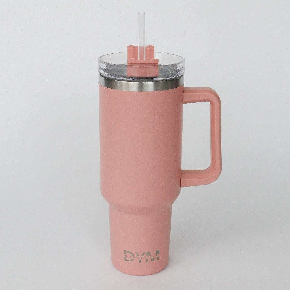 The D.Y.M 40oz Tumbler by DYM Athletics is a tall, matte pink travel mug with an ergonomic handle, clear lid, reusable straw, metallic "DYM" logo near the base, and a tapered bottom to fit car cup holders. BPA-free; shown on a plain white background.