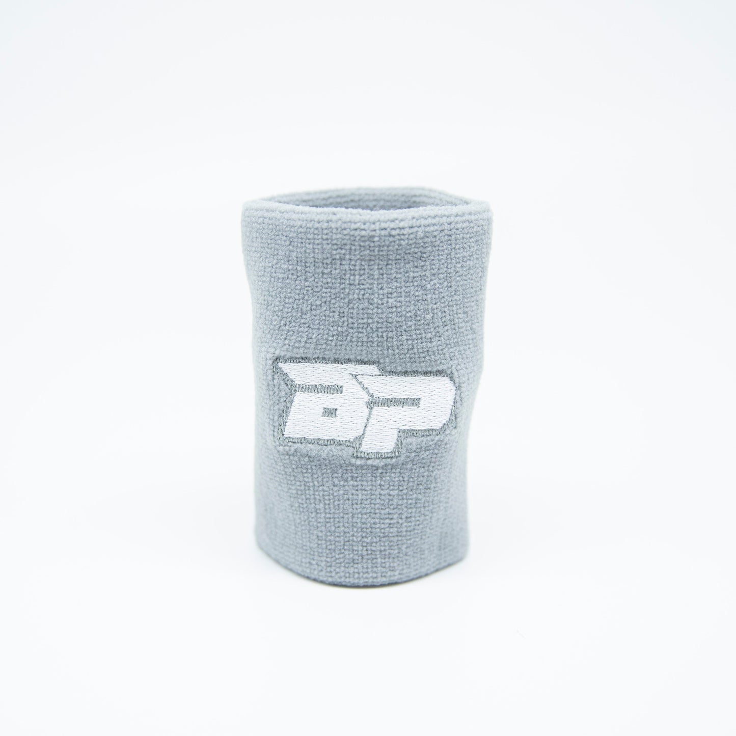 The Bodhi Performance Wristband (1pc) in light gray stands upright on a white background, showcasing a white and gray embroidered BP logo. This sweat-wicking band offers a minimalist, sporty style for high-performance play.