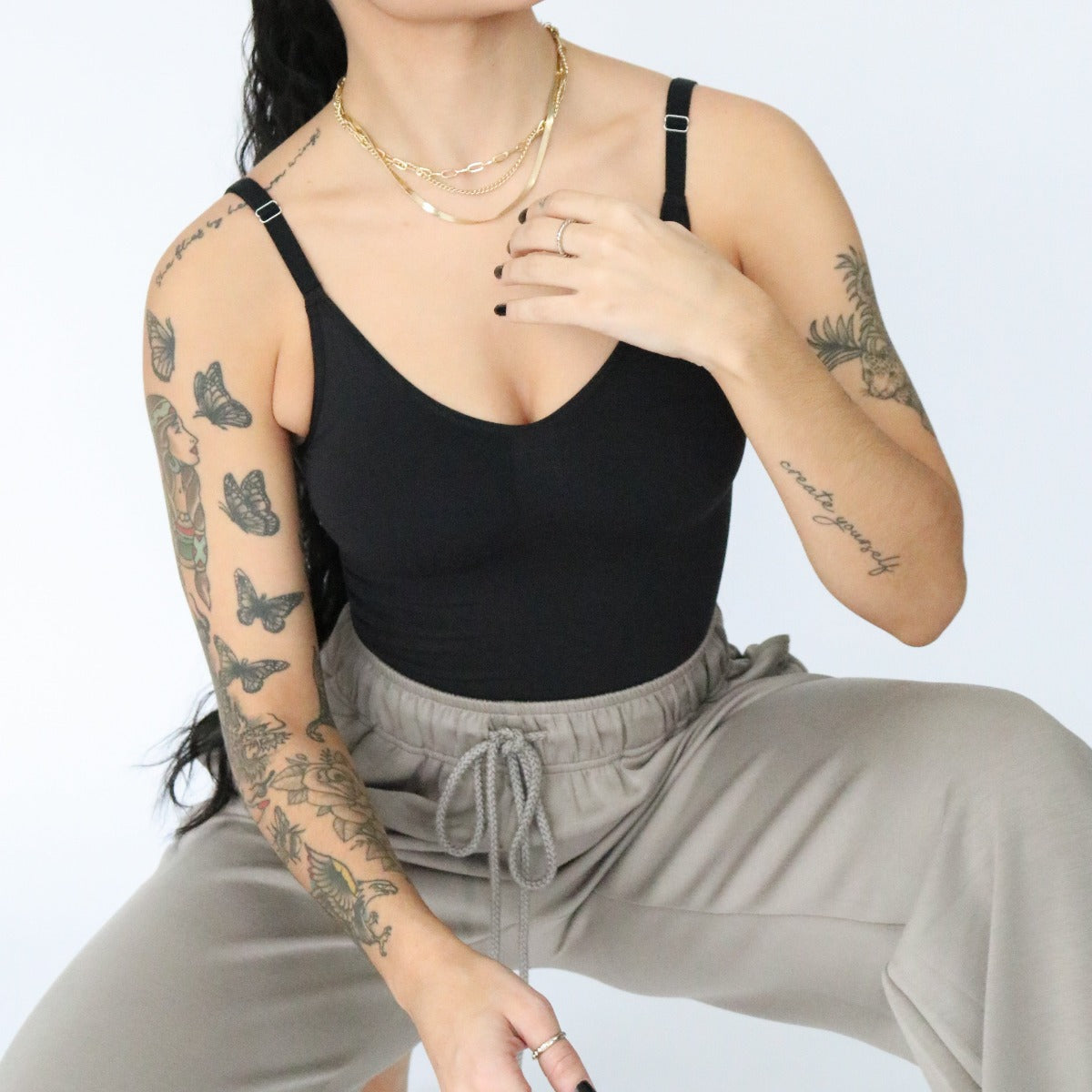 A tattooed woman exudes confidence wearing the DYM Athletics Shapewear Bodysuit.