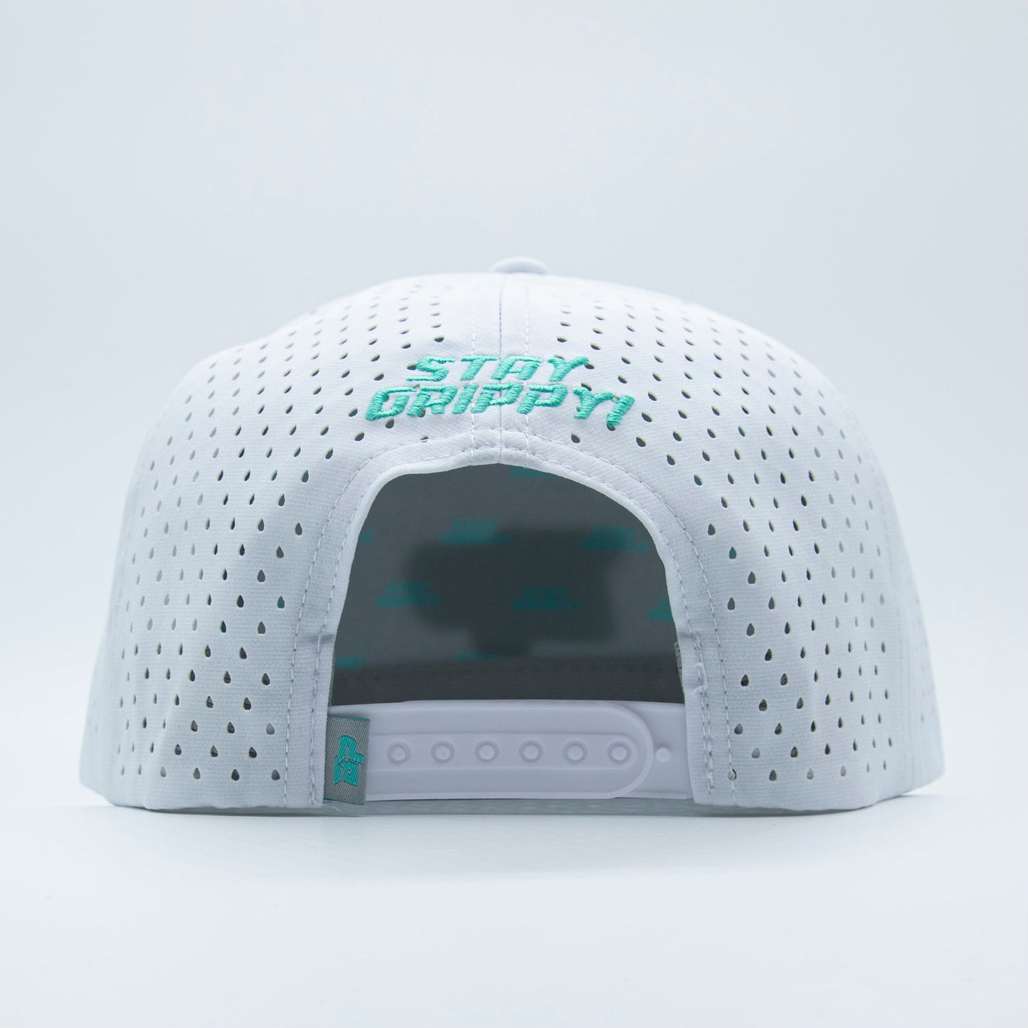 The Bodhi Performance ICON Snapback is shown from the back, with teal embroidered STAY GRIPPY! above the adjustable closure. This white perforated hat offers ventilation and features a teal logo tag on the strap.