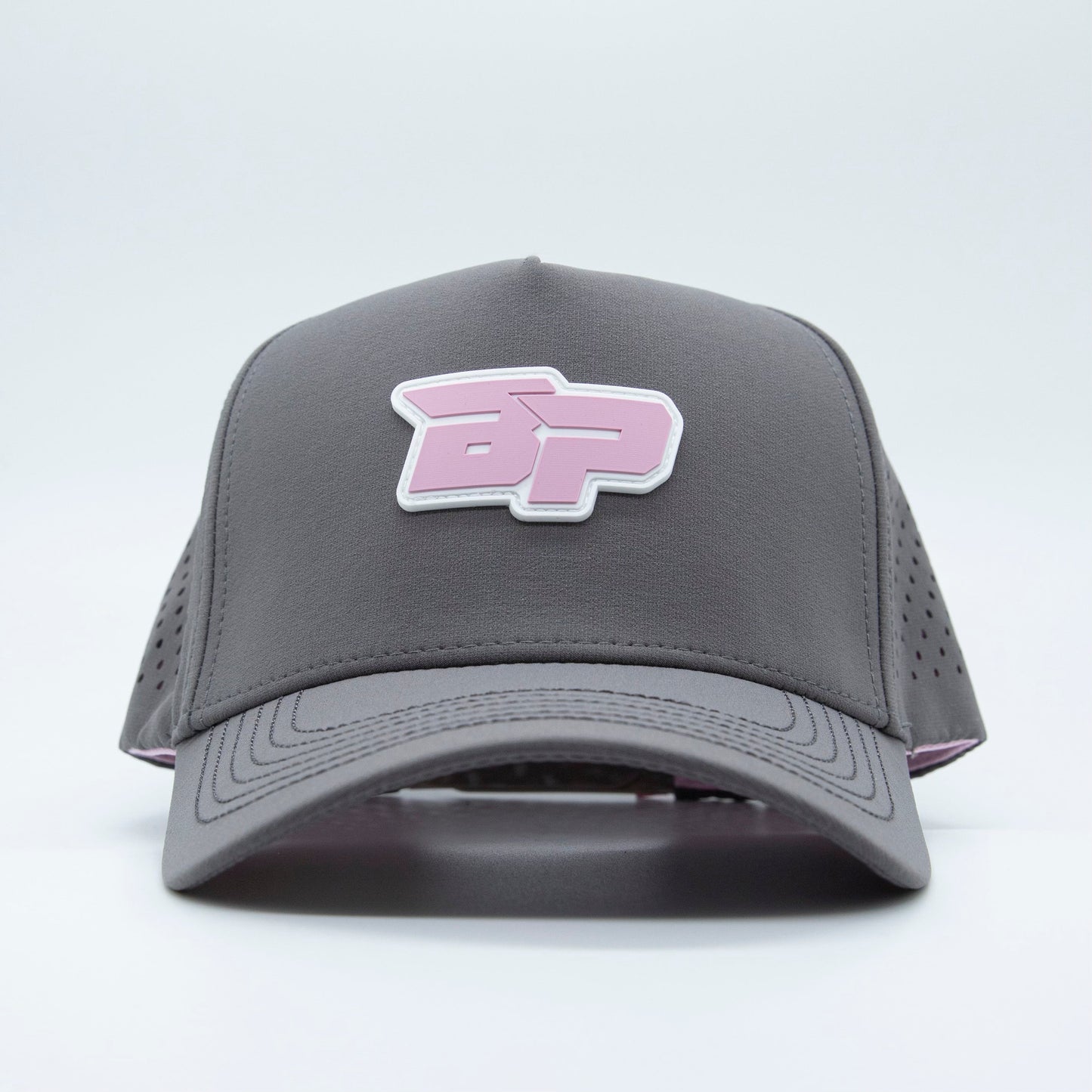 The ICON Snapback by Bodhi Performance is a gray pickleball hat with a curved brim, a raised pink and white "BP" logo on the front, and ventilated side perforations—all shown against a plain white background.