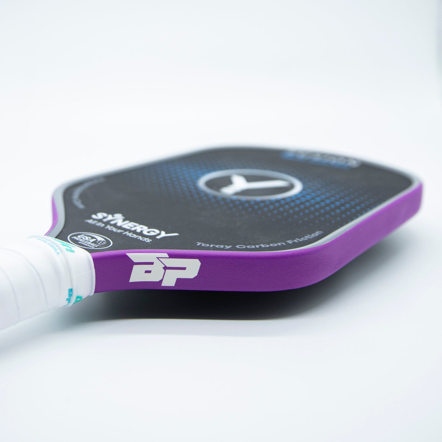 A close-up of Bodhi Performance’s black and purple paddle with Premium Edge Tape - SOLIDS for extra protection, a textured surface, white grip, and bold “BP” logo rests on a white surface, showcasing its premium details.