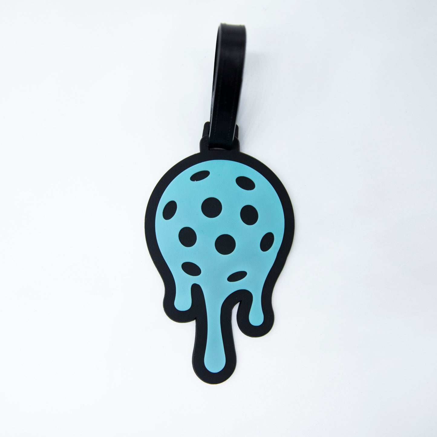 The Bodhi Bag Tags by Bodhi Performance are sky-blue, sphere-shaped luggage tags with black spots and a dripping effect. Featuring a black outline and strap, these unique pickleball bag tags are perfect for tournaments.