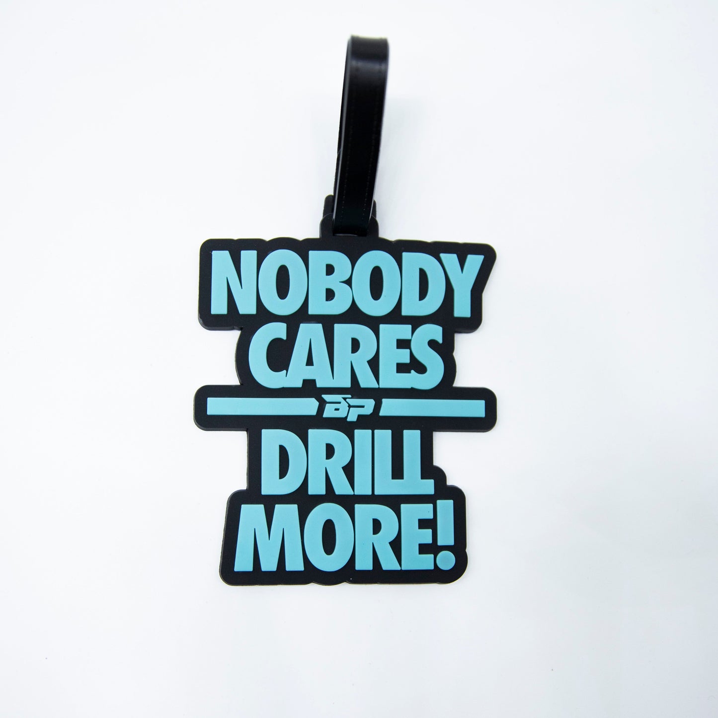 The Bodhi Bag Tags by Bodhi Performance feature a black and blue rubber design with "NOBODY CARES DRILL MORE!" and the “BP” logo, making them a standout pickleball accessory against a plain white background.