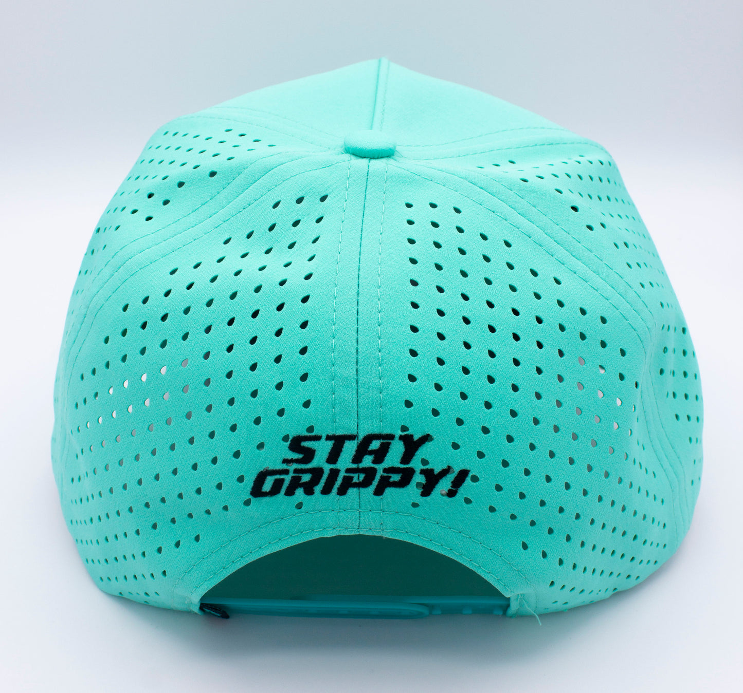A teal ICON Snapback by Bodhi Performance is shown from the back, displaying multiple small ventilation holes and “STAY GRIPPY!” embroidered in black above the adjustable strap. The background is plain white.