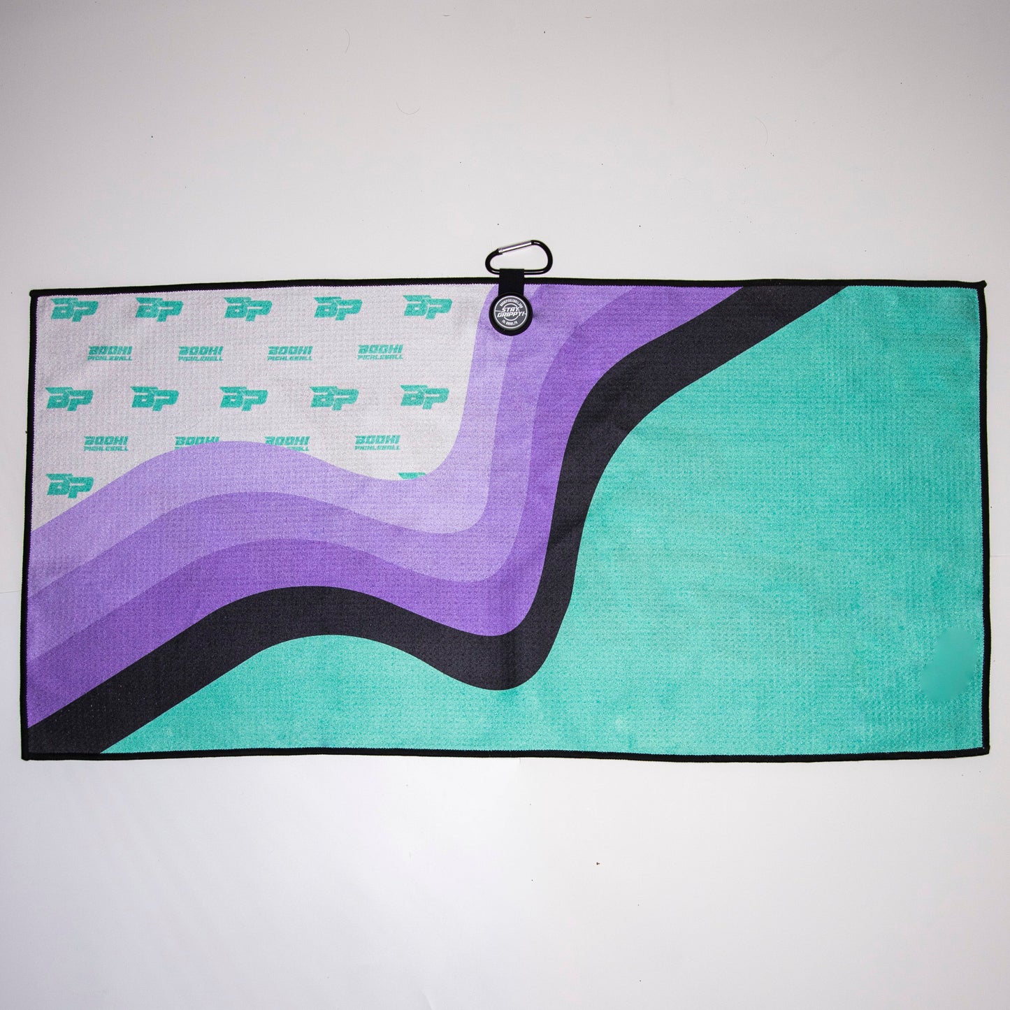 The Bodhi Performance Pickleball Towel hangs on the wall, bringing vibrant color and style to your pickleball accessories collection.