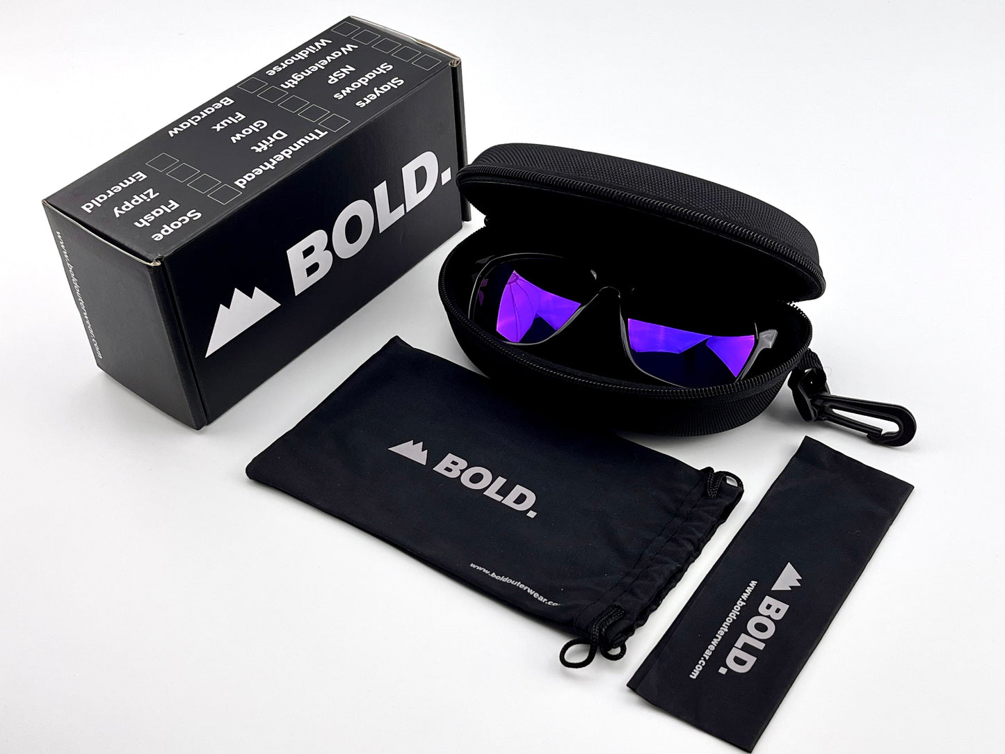 The BOLD Thunderhead Performance Sunglasses by boldouterwear feature purple fixed-tint UV-protective lenses. They come in a black zippered case, with a branded drawstring pouch and cleaning cloth, plus a sporty mountain-logo box.