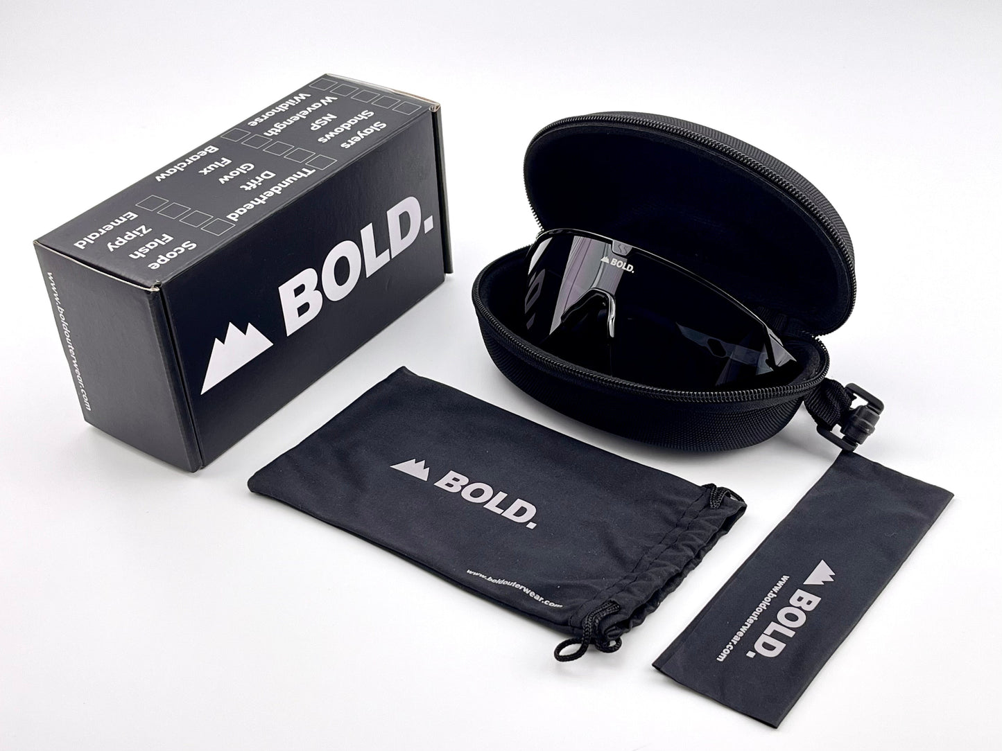 The BOLD Bearclaw Performance Sunglasses by boldouterwear, with reflective lenses and a shield-style frame, rest in an open zippered case beside a BOLD. box and two branded pouches—ideal for MTB, ski, running, and more.