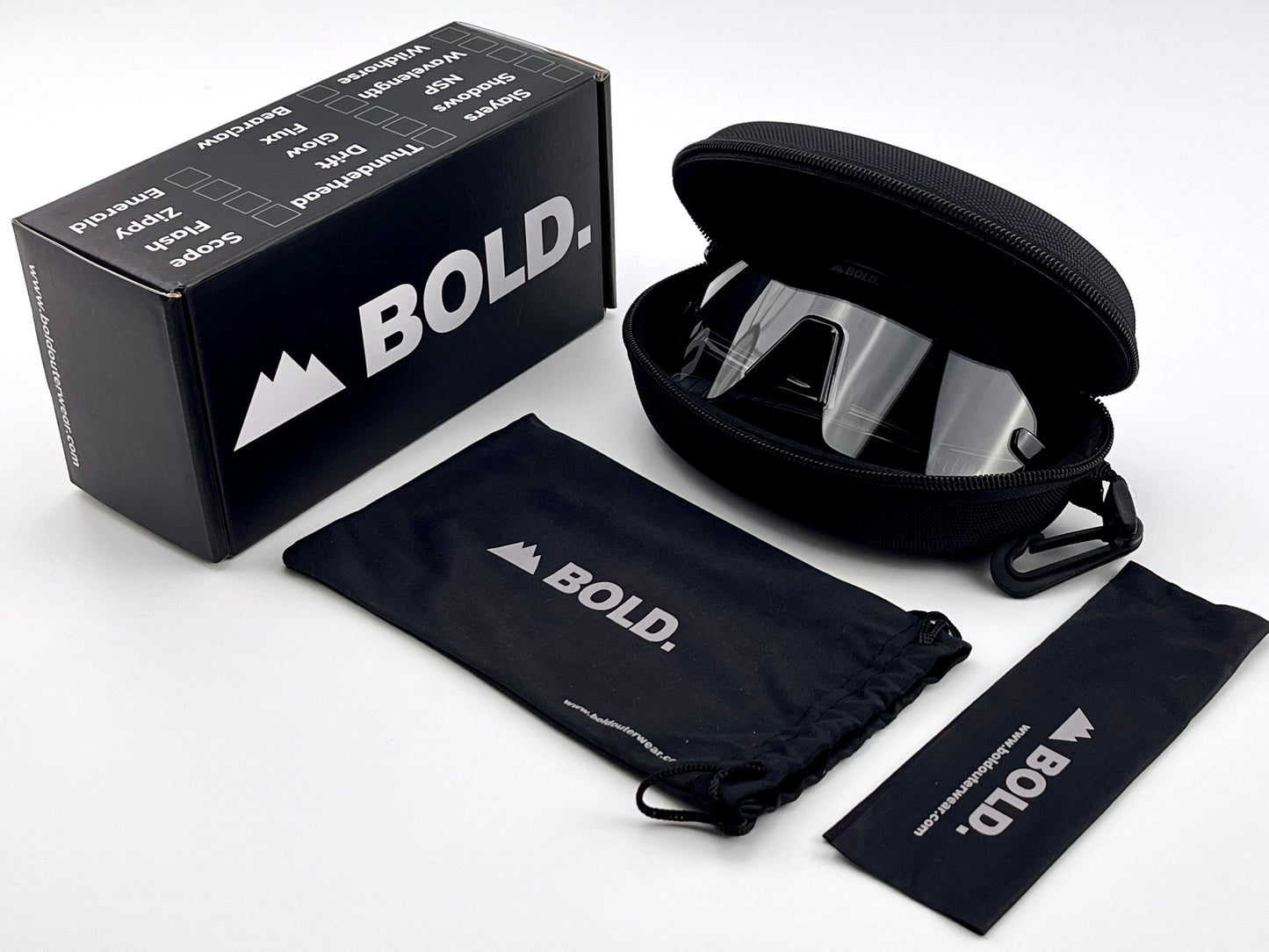 The BOLD Emerald Photochromic Sunglasses by boldouterwear come in a black hard case, with a black drawstring pouch and a smaller pouch. The upright branded box highlights features like anti-fog, UV protection, and all-terrain clarity.