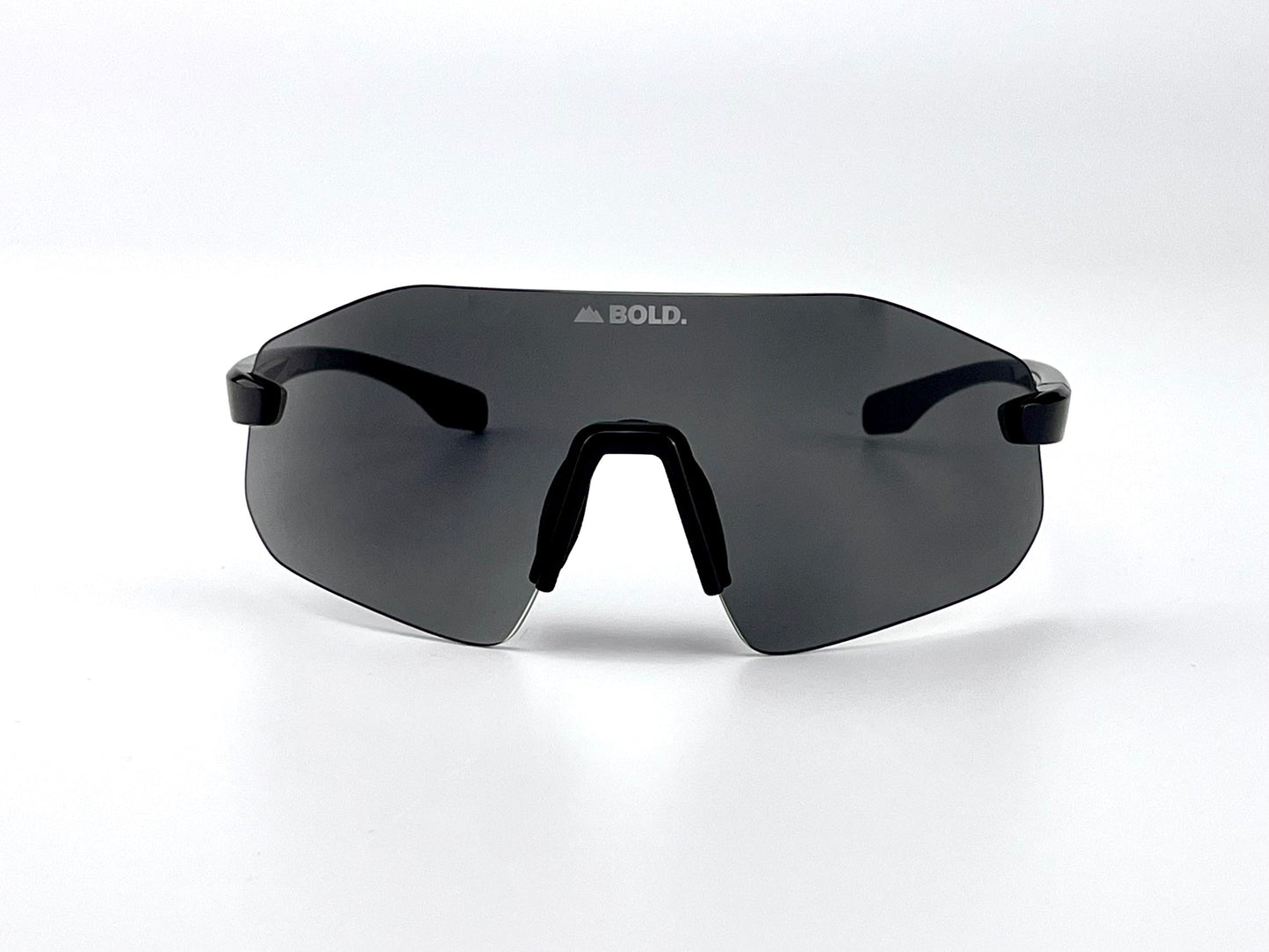 The BOLD Emerald Photochromic Sunglasses by boldouterwear feature a minimalist black frame, sleek wraparound dark lens, and white “BOLD.” triangle logo. Adaptive photochromic lens provides all-terrain clarity for MTB, ski, and lifestyle use.