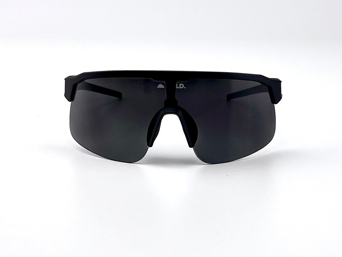 The BOLD Zippy Photochromic Sunglasses by boldouterwear feature a sleek black wraparound visor-style lens, a minimal frame with thick arms, and a prominent nose piece, shown resting on a plain white surface. Ideal for MTB, ski, and lifestyle wear.