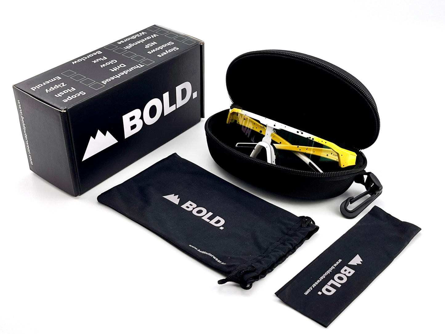 A pair of yellow and white BOLD Zippy Photochromic Sunglasses by boldouterwear rests in an open black zip case. Nearby are a branded pouch, cleaning cloth, and a mountain-logo BOLD box, all well-lit on a white background.