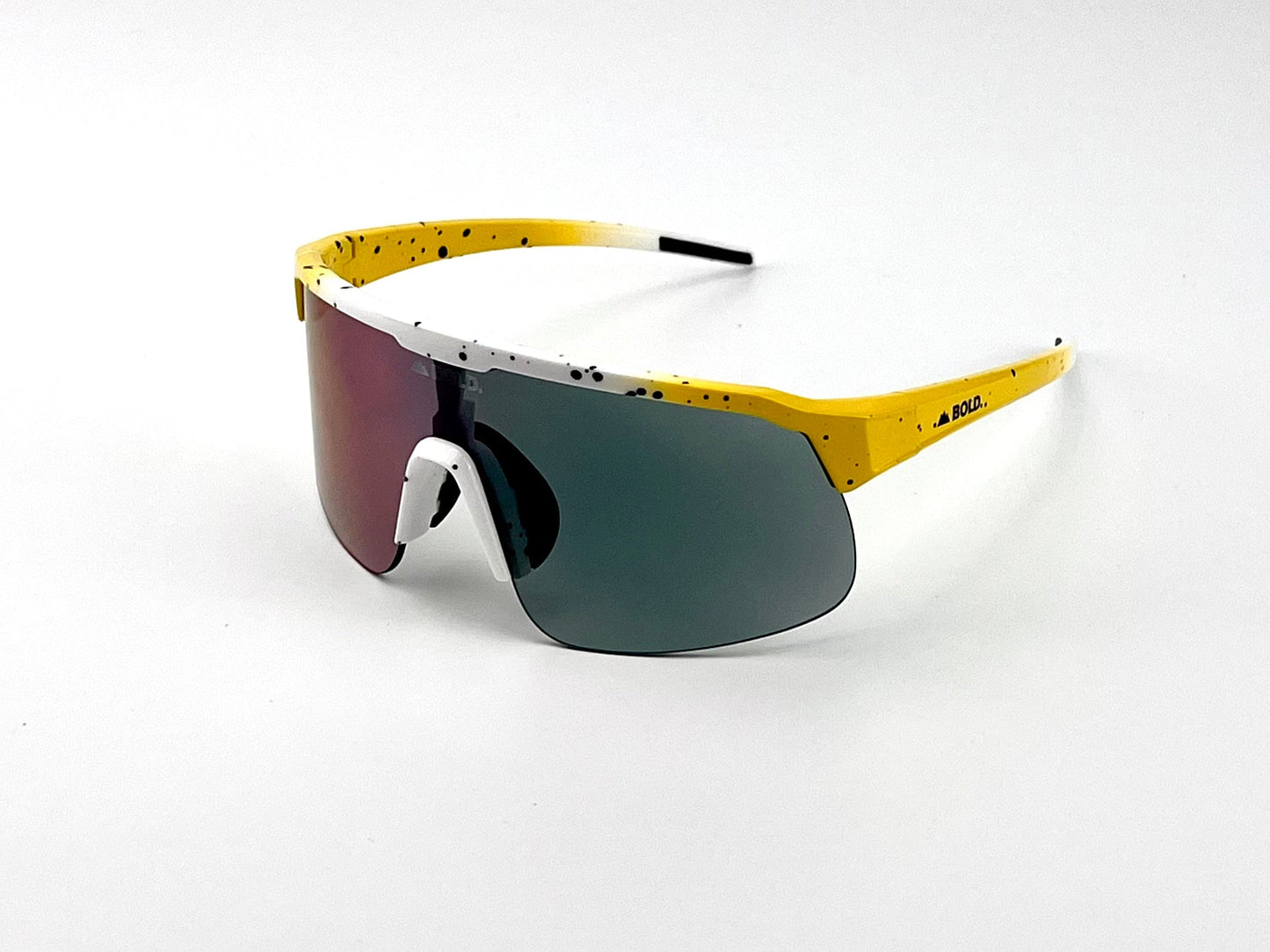 The BOLD Zippy Photochromic Sunglasses by boldouterwear feature a sporty, lightweight yellow frame with black speckles, white accents, a single mirrored lens, angular arms, and white nose pads—ideal for MTB, ski, and lifestyle use.