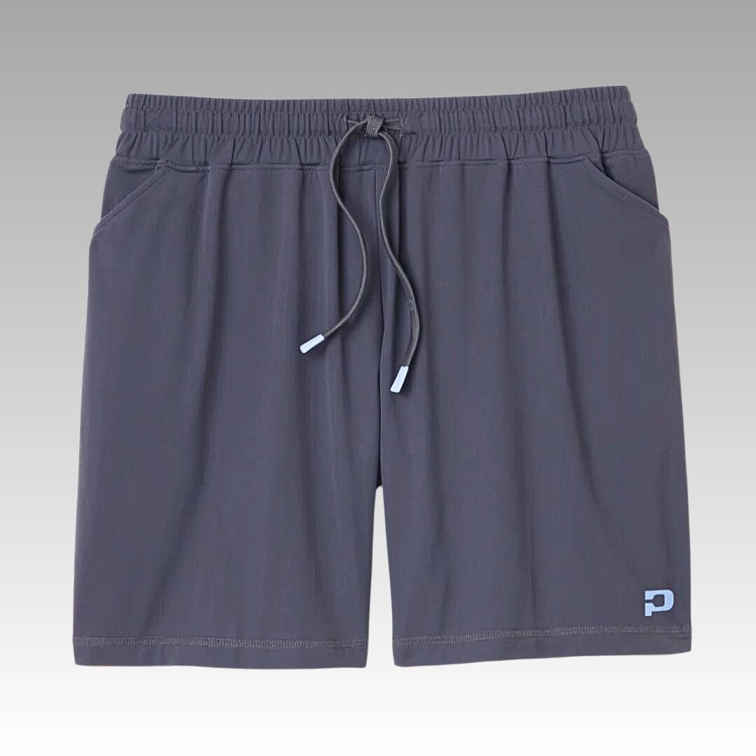 The Playly Store Kelter Short is a pair of dark gray men’s athletic shorts made from SofKnit fabric, featuring an elastic waistband, drawstring, side pockets, and a blue and white logo on the lower right leg. Light gray gradient background.