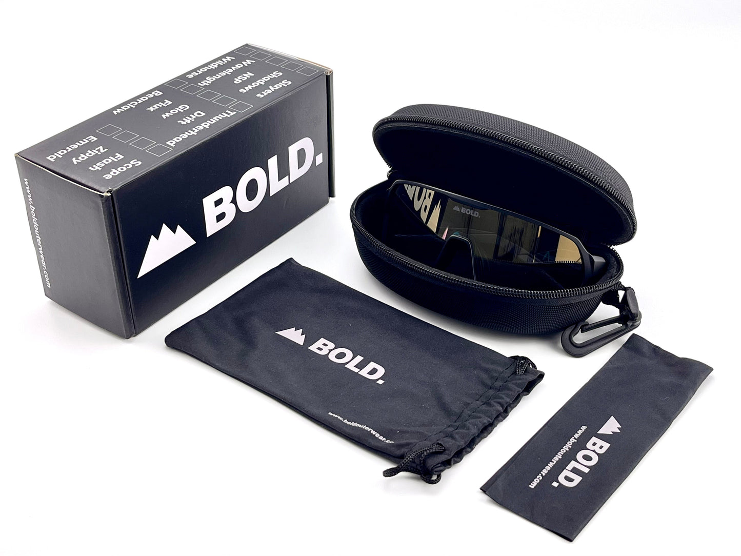 The BOLD Glow Photochromic Sunglasses by boldouterwear rest in a zippered hard case with carabiner, beside a black “BOLD” drawstring pouch and cleaning cloth. A branded black box with white text and mountain logo completes the set.