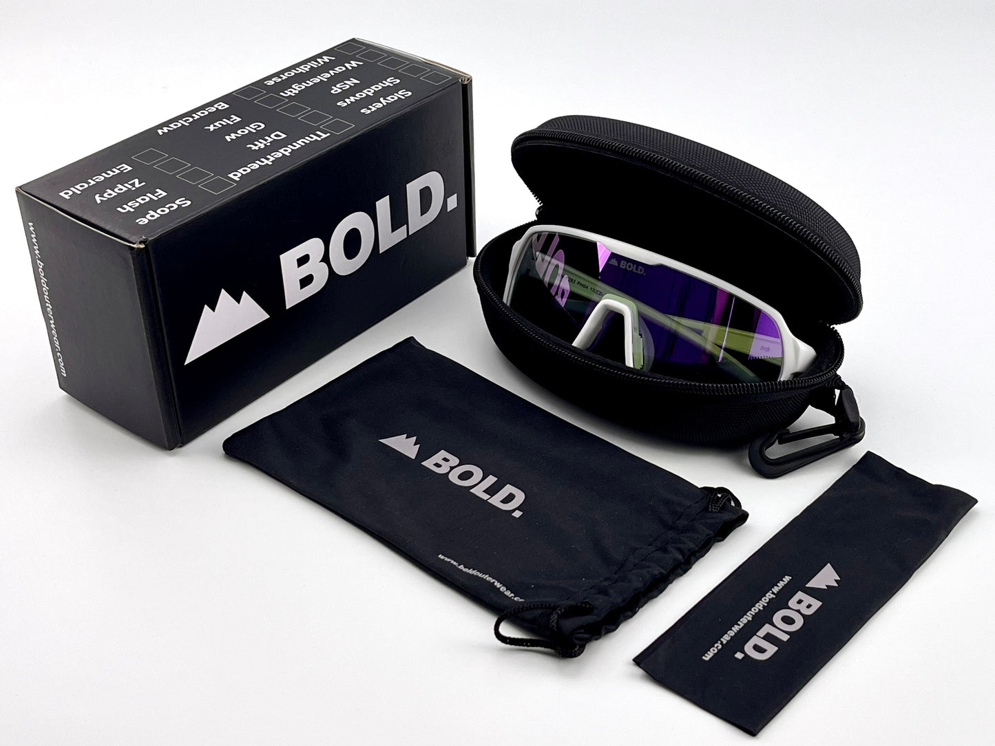 The BOLD Drift Photochromic Sunglasses by boldouterwear, with white frames, are displayed in an open black zippered case beside a branded box, drawstring pouch, and cleaning cloth on a white background.