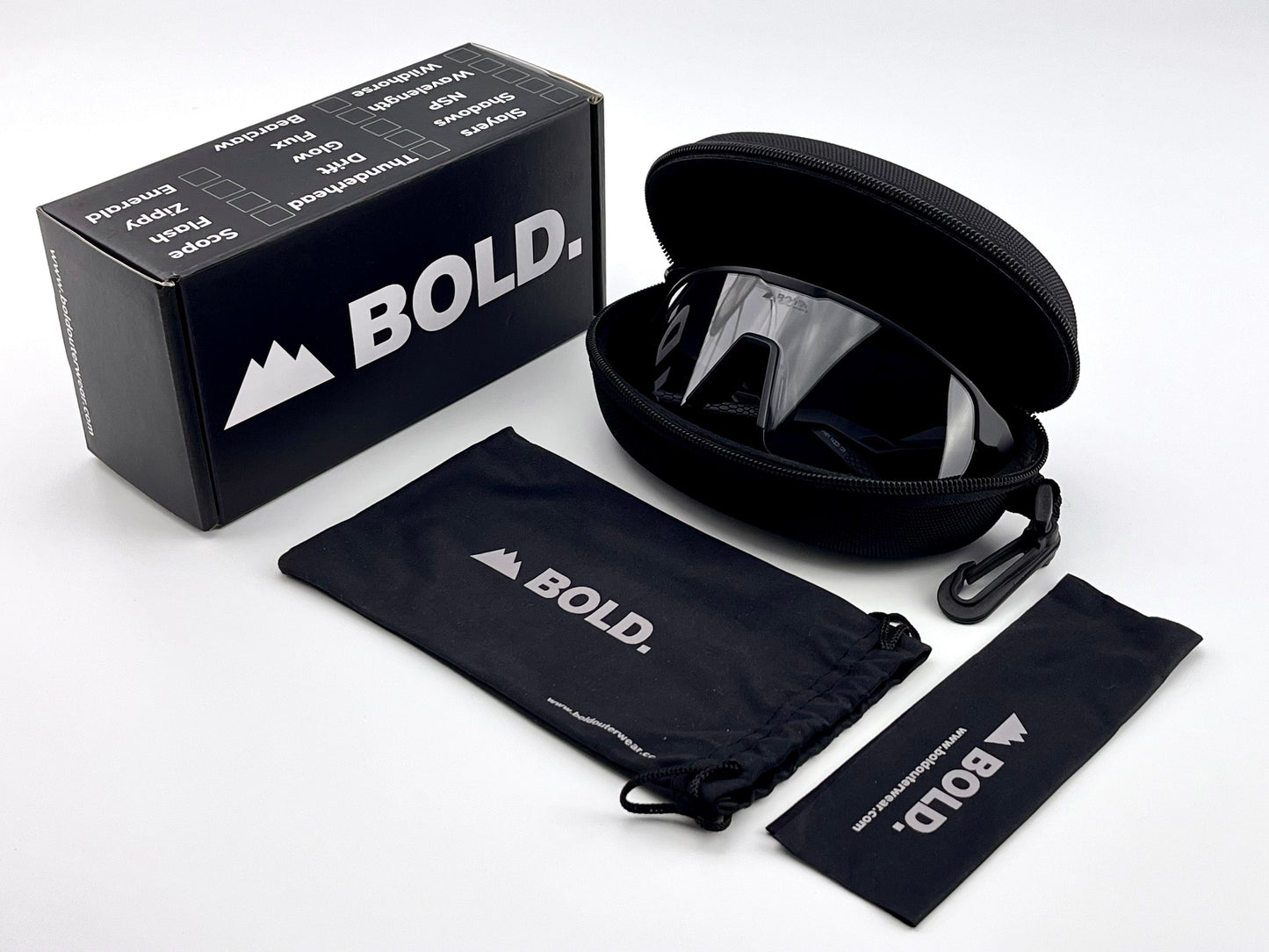 A black box labeled boldouterwear sits beside a zippered case containing BOLD Flash Photochromic Sunglasses—sporty, light-adaptive eyewear with mirrored lenses. Nearby are a branded pouch and lens cloth, all on a white background.