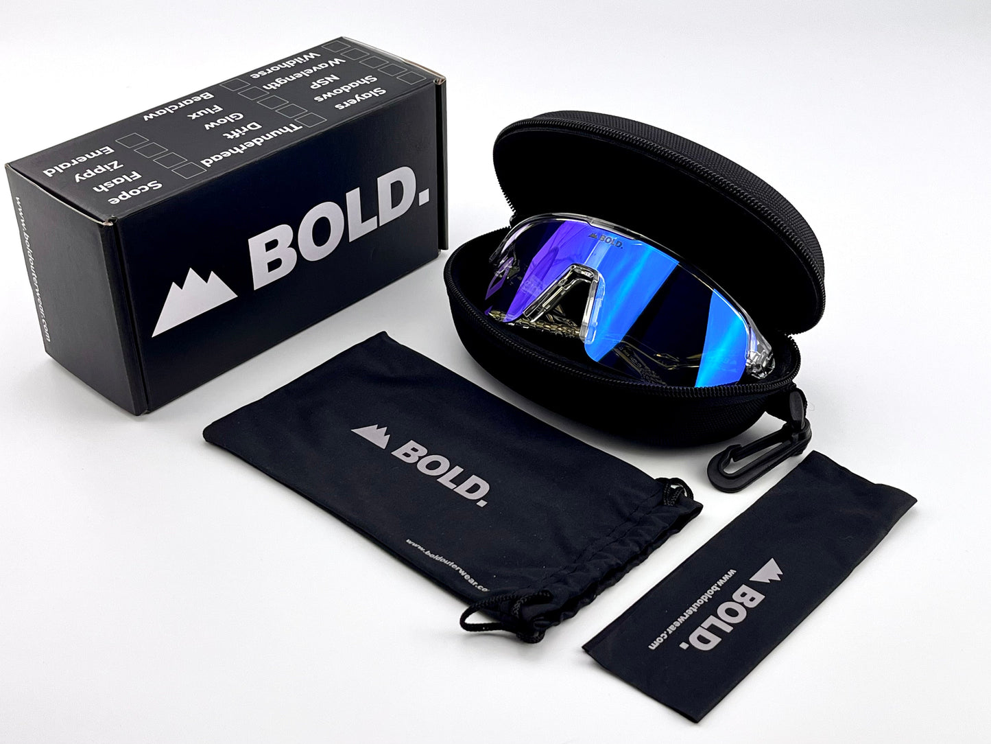 The BOLD Flash Photochromic Sunglasses from boldouterwear, with reflective blue lenses, are in a black zippered case. Nearby: a black box with logo and motivational words, drawstring pouch, and cleaning cloth on a white surface.