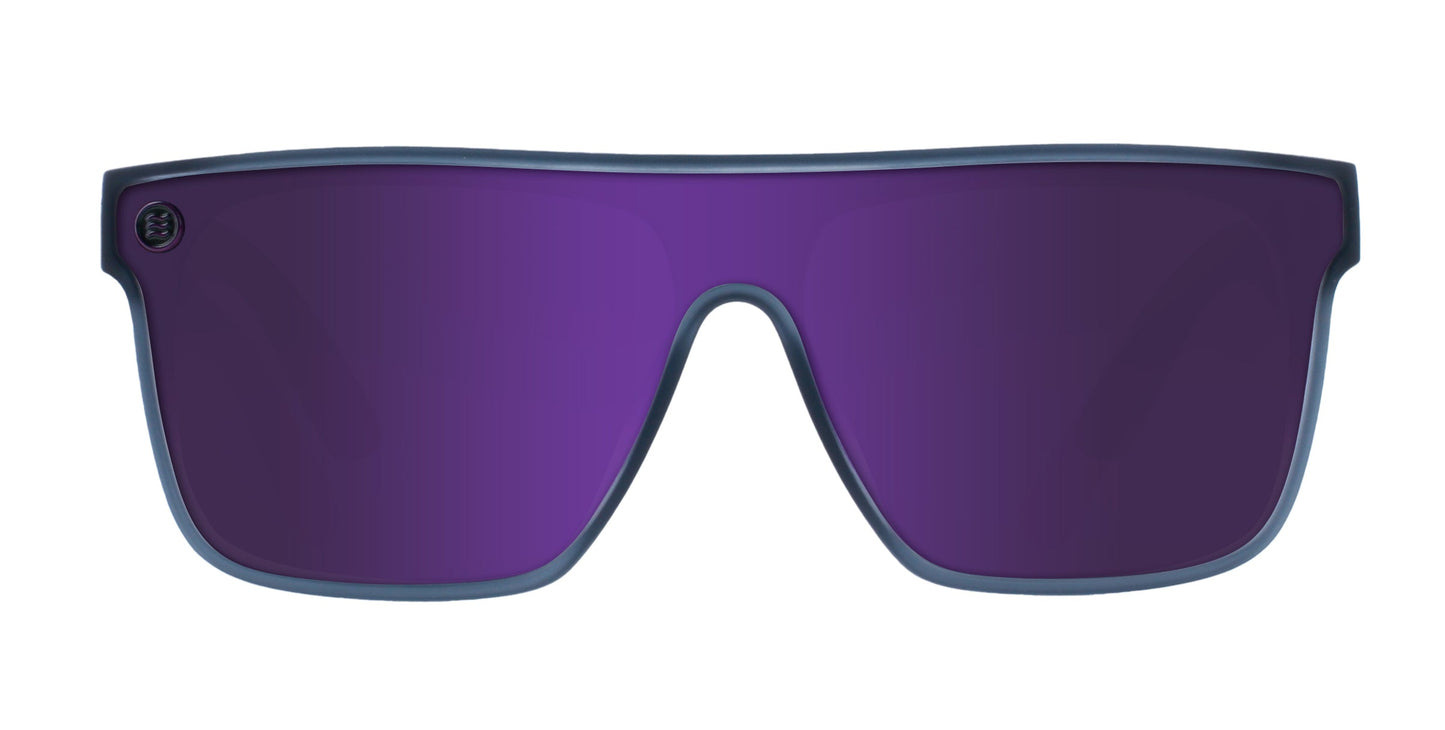 The Neven Eyewear 53X sunglasses feature a sleek, single-piece purple polarized lens with UV400 protection, a thin dark blue frame, and an integrated bridge. A small decorative emblem sits on the upper left corner. The background is white.