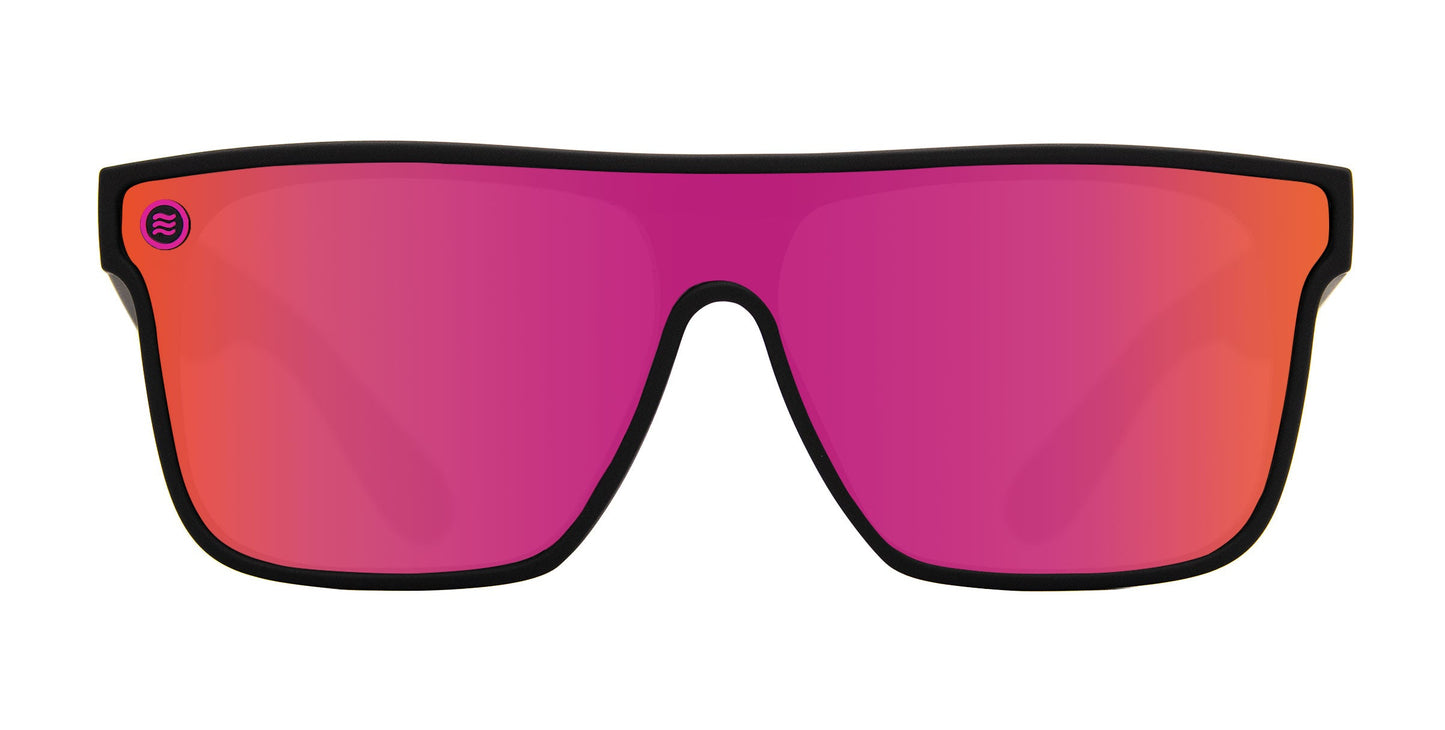 Front view of Neven Eyewear Bliss sunglasses in hot pink with a wide, mirrored single-piece lens and thin black frame. Sporty design features UV400 protection and a small circular purple logo on the top left of the lens.