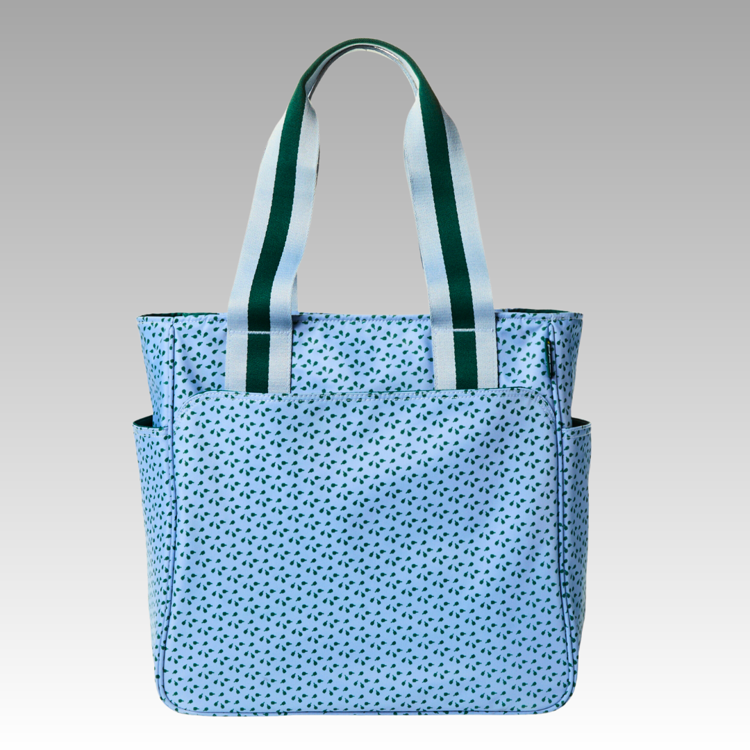 The Playly Store Lulu Pickleball Tote features a light blue design with small dark blue dots, two wide white handles with dark green stripes, and side pockets. This stylish accessory is perfect for every pickleball player.
