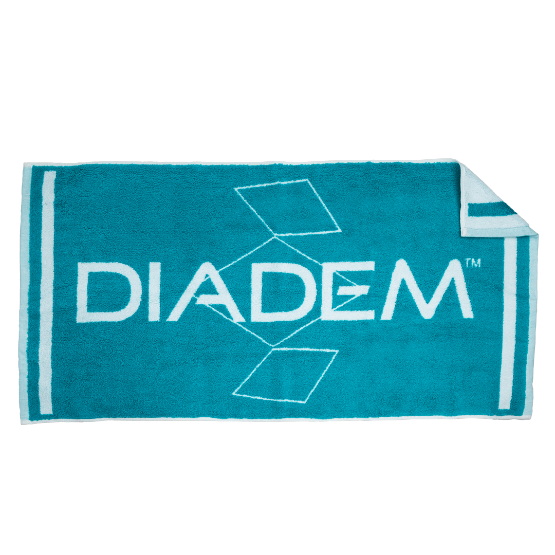 The Diadem Sports Towel is a small turquoise rectangle (24.5" x 12") with “DIADEM” in bold white, diamond shapes above and below the text, two white stripes near each end, and a slightly folded upper-right corner showing the underside.