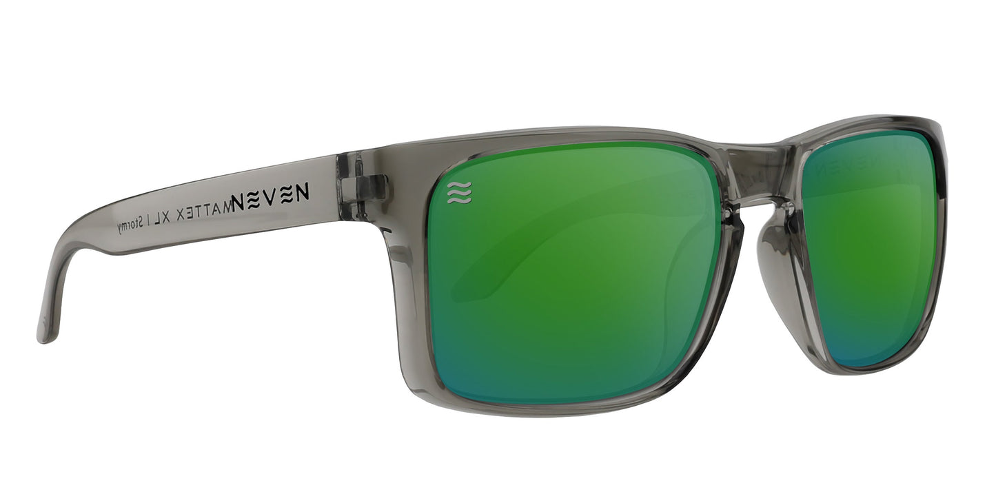 The Neven Eyewear Stormy XL features oversized translucent gray frames with a glossy finish, green mirrored polarized lenses, and silver branding with wavy lines on the left arm for a modern look.