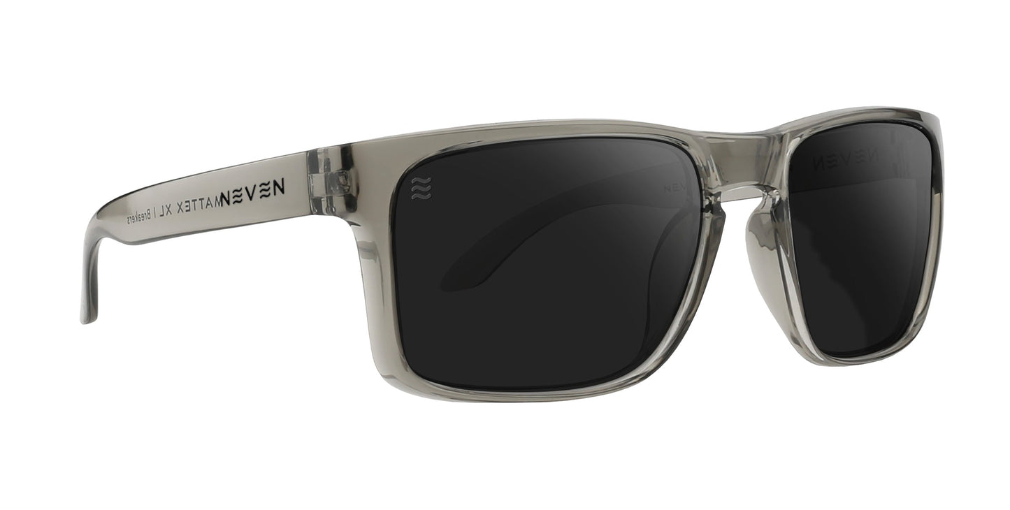 The Breakers XL by Neven Eyewear are oversized sunglasses with translucent gray frames and solid black lenses. "NEVEN" is printed on the left arm, and the modern design features slightly thick, straight arms.