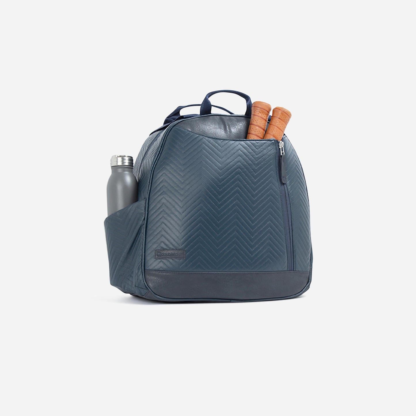 The Doubletake MELBOURNE Pickleball Backpack & Tote in blue chevron sits on a white background, featuring water-resistant fabric, front zipper pocket, top handle, a silver water bottle in one side pocket, and two brown rolling pins inside.