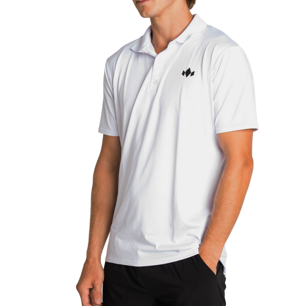 A man wears a Diadem Sports - Men's Essential Everyday Top, a white short-sleeve polo with a small black geometric logo on the left chest, athletic fit. He stands with one hand in black pants pocket; head cropped, plain white background.