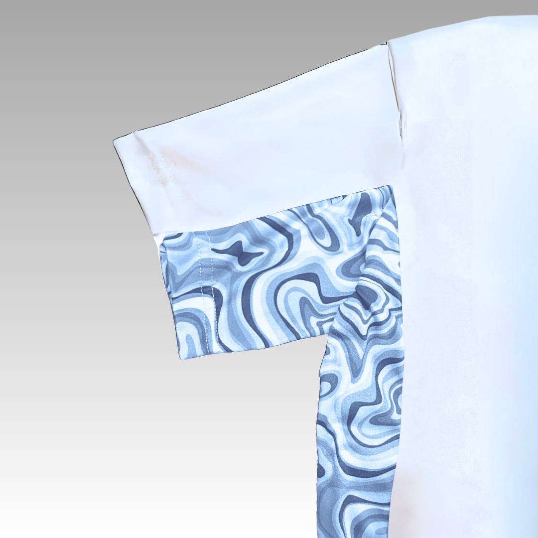 The Playly - Warrior Tee 2.0 from Playly Store is a white short-sleeve shirt with a single sleeve and side panel in a blue and white wavy pattern, set against a light gray to white fade—ideal as a pickleball performance shirt.