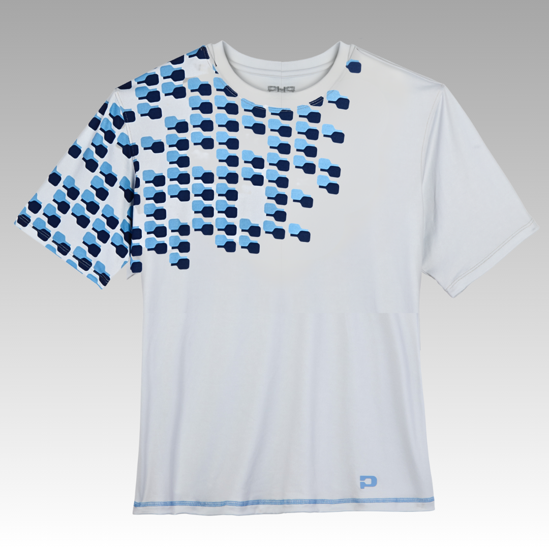 The Playly Store Warrior Tee 2.0 is a white athletic t-shirt with overlapping blue and navy geometric squares on the left chest, a fade design, moisture-wicking fabric, and a small blue logo at the hem.