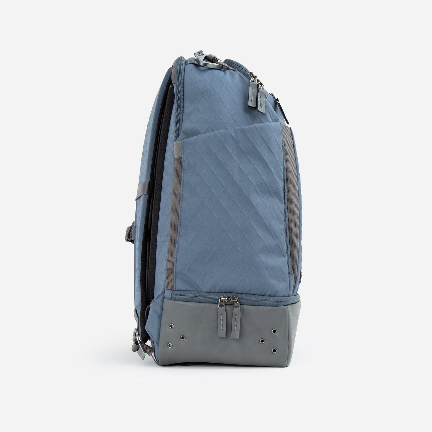 The Doubletake NYC Pickleball Backpack is displayed upright, side view, in blue with diamond-patterned fabric and gray accents. It features padded shoulder straps, dual zippers on the paddle compartments, and extra zippers on the main compartment. White background.