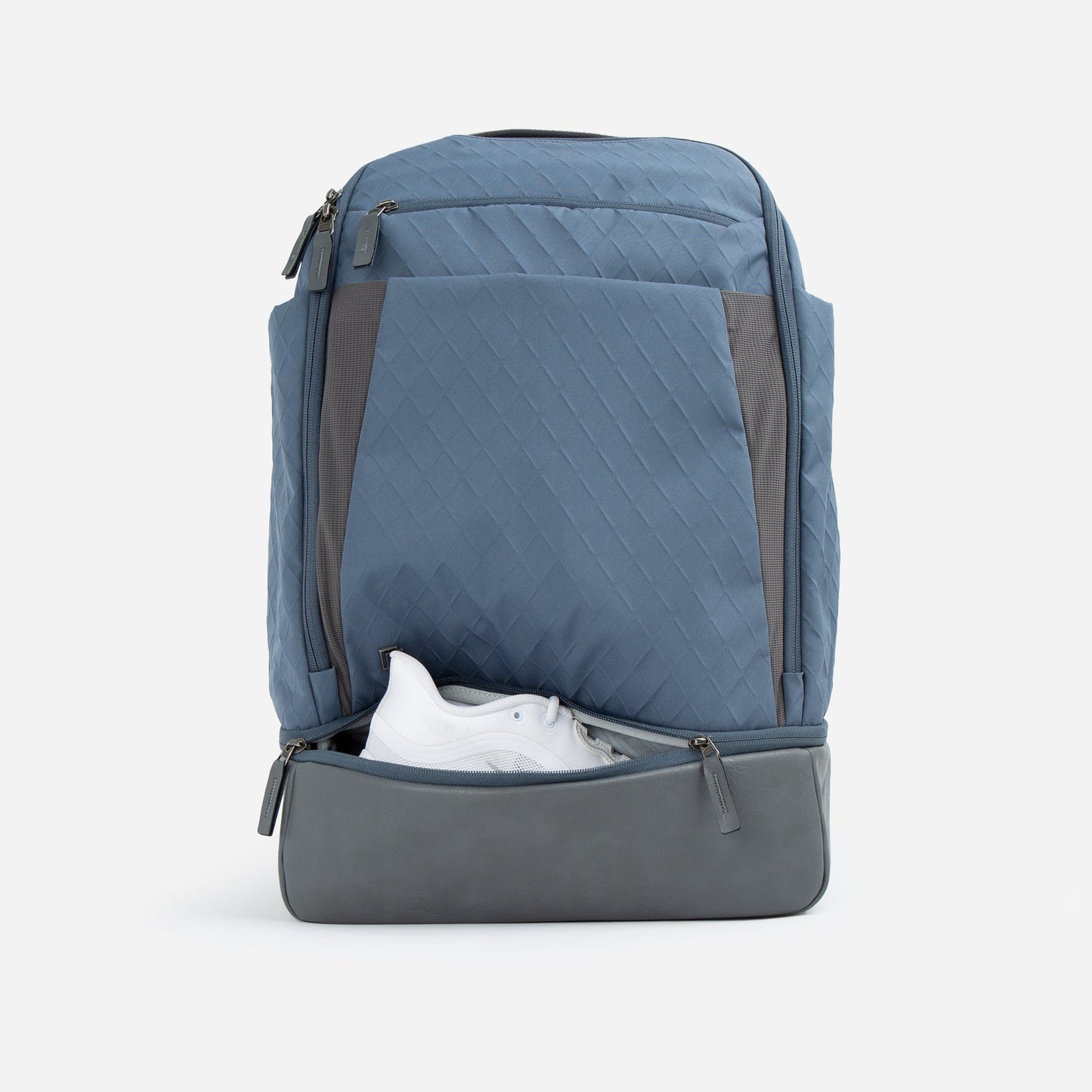 The Doubletake NYC Pickleball Backpack, in light blue with gray accents and a quilted texture, is displayed upright on a white background. The unzipped front pocket reveals white sneakers, and the bag features paddle compartments.