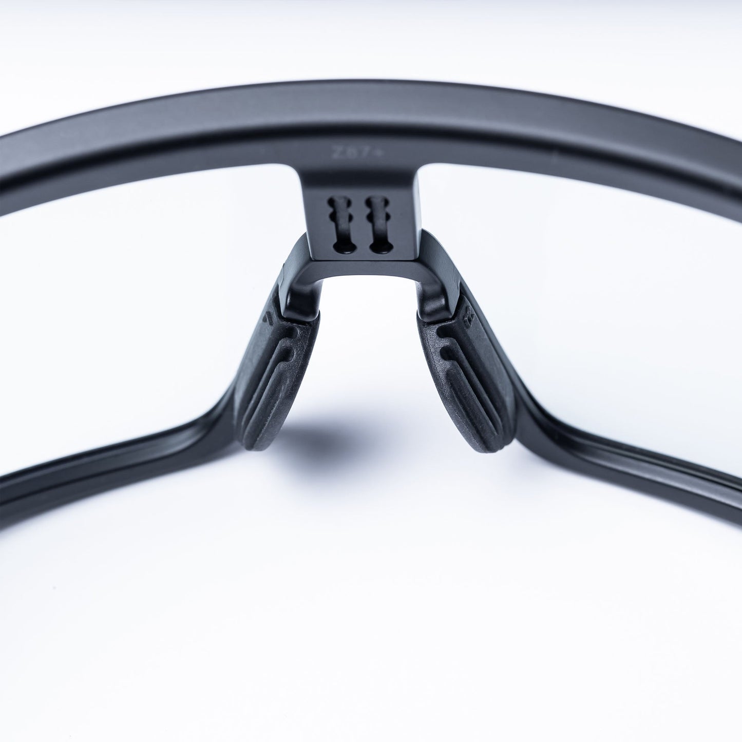 Close-up of the adjustable FOCOS ANKR™ Nose Pads by BRIOTI on black frames, highlighting the central support area and replacement pads against a white background with soft lighting.