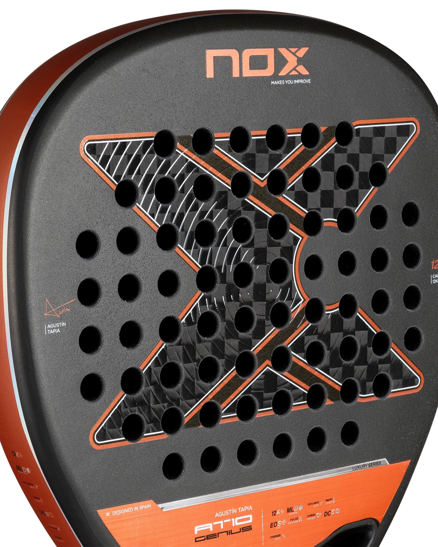 Close-up of the Nox AT10 Luxury GENIUS ATTACK 12K 2025 by Agustin Tapia for Padel USA—a diamond racket with black 12K carbon, silver “X” design, checkered pattern, EXCLUSIVE SPIN tech, round holes, orange trim, and NOX branding.