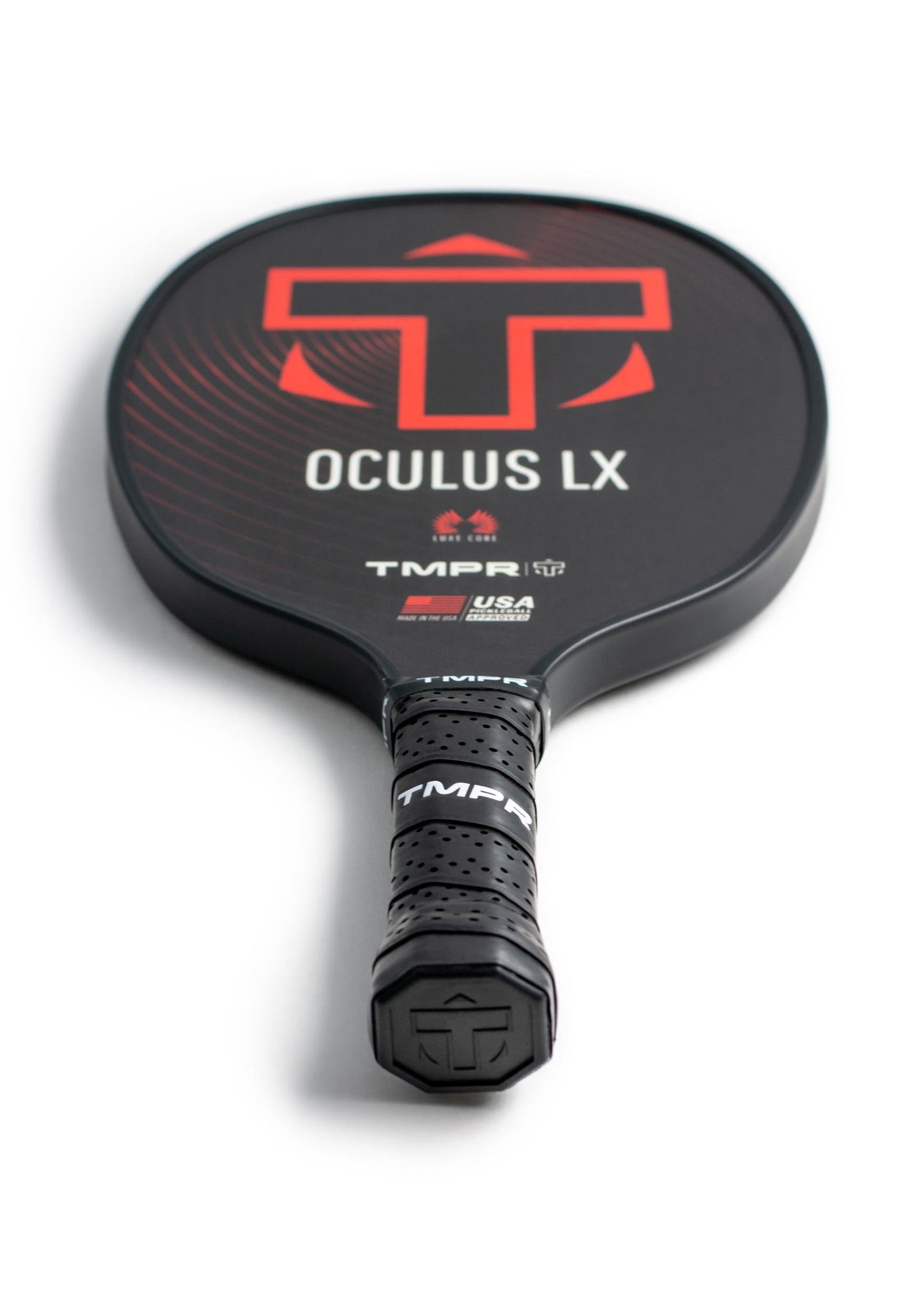A black TMPR Sports Oculus LX pickleball paddle rests face-up, featuring a bold red and white TMPR logo, Luxe Core technology, and a textured handle wrapped in perforated grip tape.