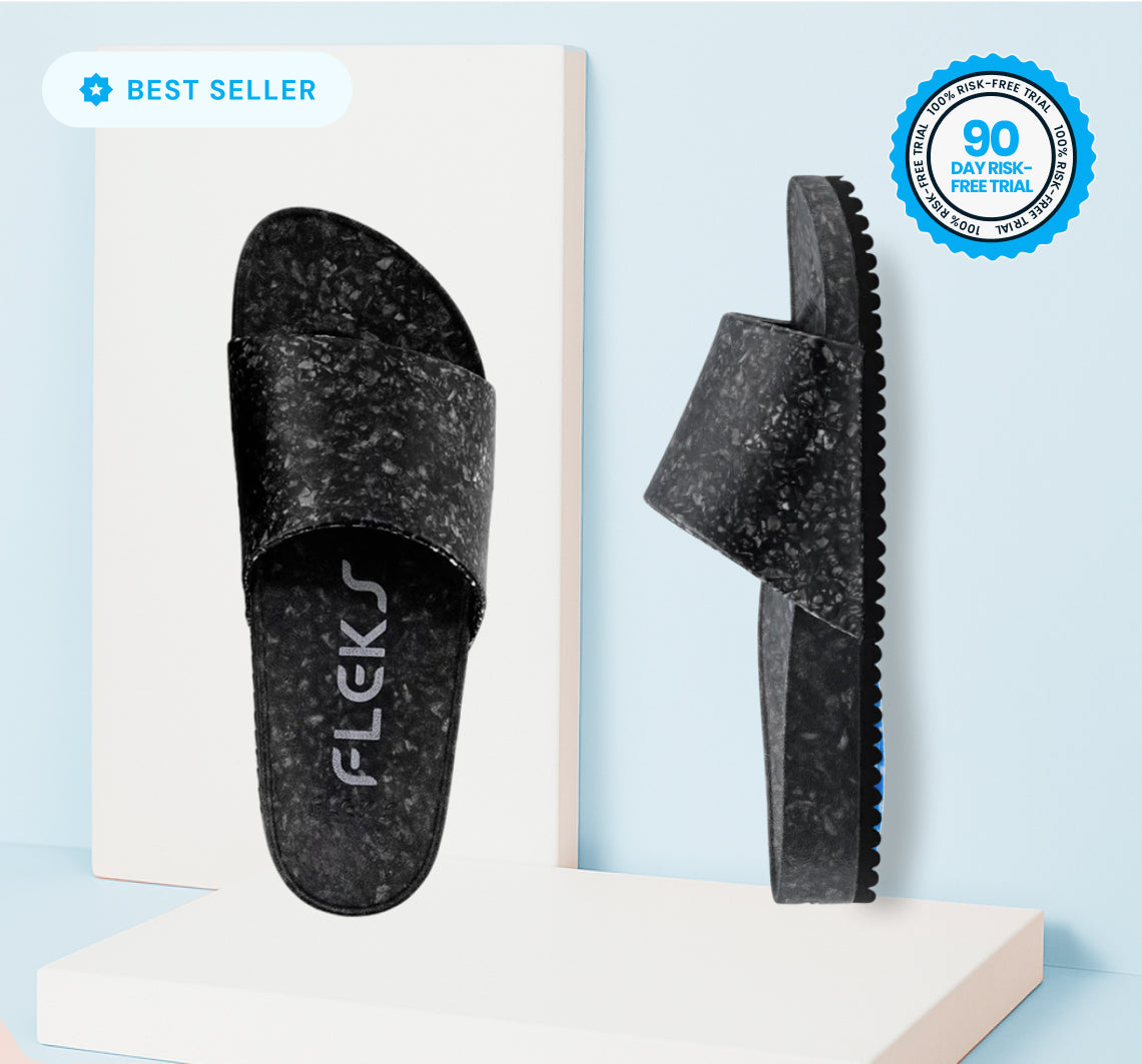 The Blumaka Fleks® East Beach Slide is a black slipper with a white surface, designed to support proper alignment and relieve soreness—ideal for athlete recovery.