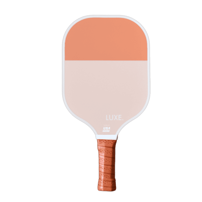 The LUXE Pickleball Dipped - Leisure paddle features a rectangular shape, honeycomb polymer core, smooth edges, and a two-tone fiberglass face—light peach below and dark orange above—with a textured orange grip and “LUXE.” logo.