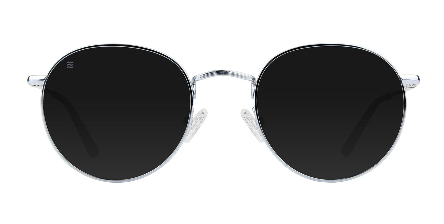The Ivy by Neven Eyewear features round black lenses, a thin stainless steel frame, and transparent nose pads. Its minimalist, classic design is highlighted in this front-facing image showing both lenses symmetrically.