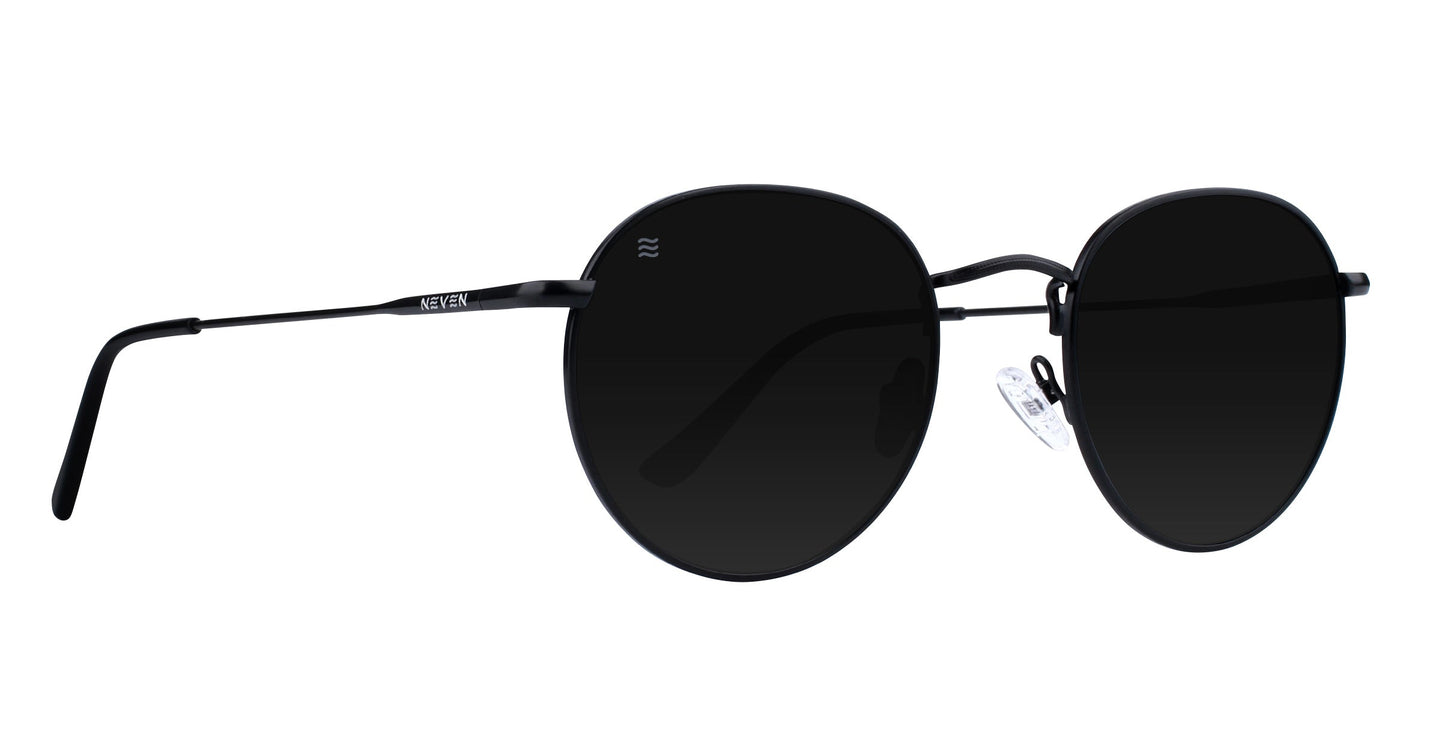 A pair of round black Saint sunglasses by Neven Eyewear with thin metal frames, black polarized UV400 lenses, clear adjustable nose pads, slim curved temples, and “Neven” branding on the left arm.