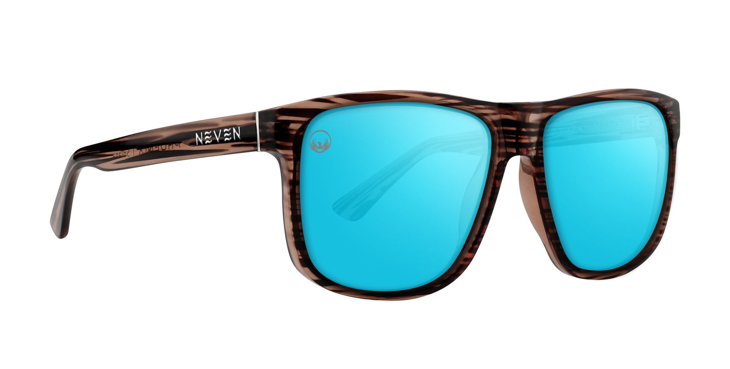 The Solana sunglasses by Neven Eyewear have a brown striped tortoiseshell wood-grain frame, bright blue mirrored lenses, a slight curve, and “NEVEN” in white on the left arm. Stylish and modern, they belong to the Phoenix Collection.