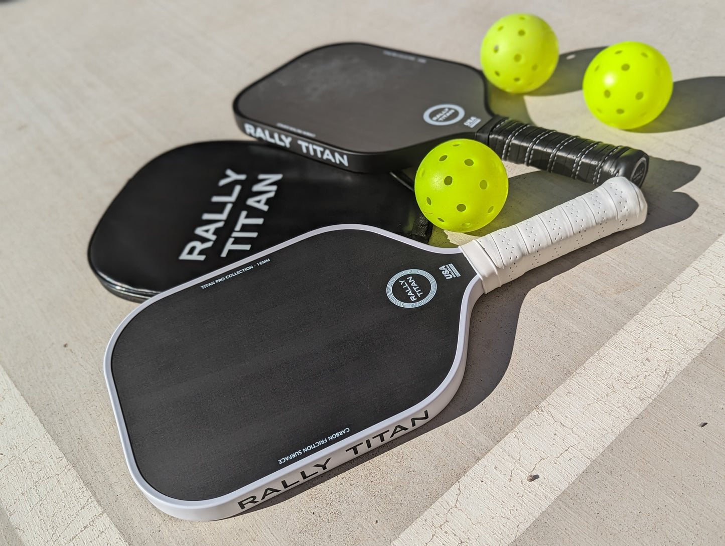 The Rally Titan Pickleball Titan Pro Control 16MM paddle with T700 carbon friction and textured surface, USAPA approved, rests on a surface alongside balls for enhanced performance.